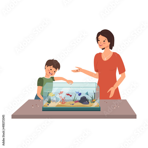 Mom and boy feed the fish in the aquarium