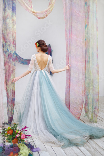 The bride has a full-length back in a wedding image on a silk wedding arch. Lush blue wedding dress and bright interior