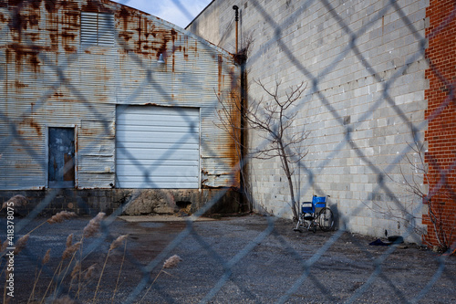 Wheelchair abandoned by a loading dock at an old rusty warehouse