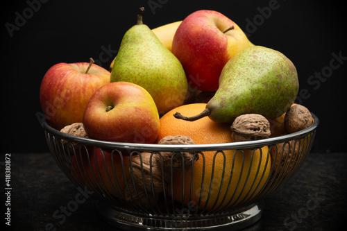 fruit bowl with apples, banana, pears, orange and walnuts