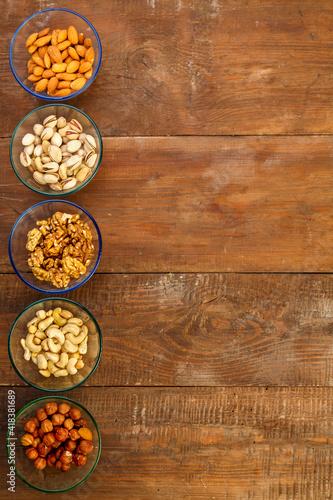 Assorted nuts in a glass bowl on a wooden table. copy space.