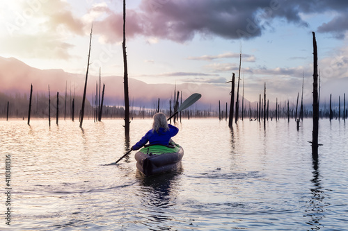 Adventurous Girl kayaking on an infatable kayak in a beautiful lake. Colorful peaceful Sunrise Art Render. Taken in Stave Lake, East of Vancouver, British Columbia, Canada. Adventure and vacation photo