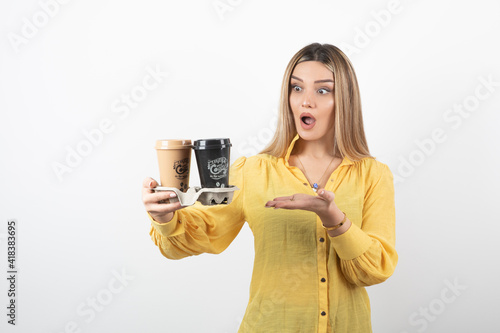 Portrait of surprised woman holding cups of coffee and standing