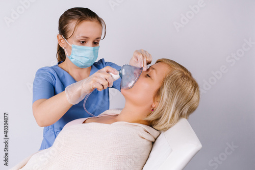 A nurse makes a nebulizer treatment for a Caucasian woman against respiratory diseases. photo