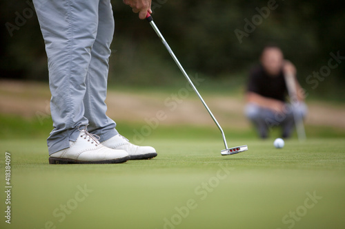 Valokuva A golfer wearing white shoes uses a putter on the putting green