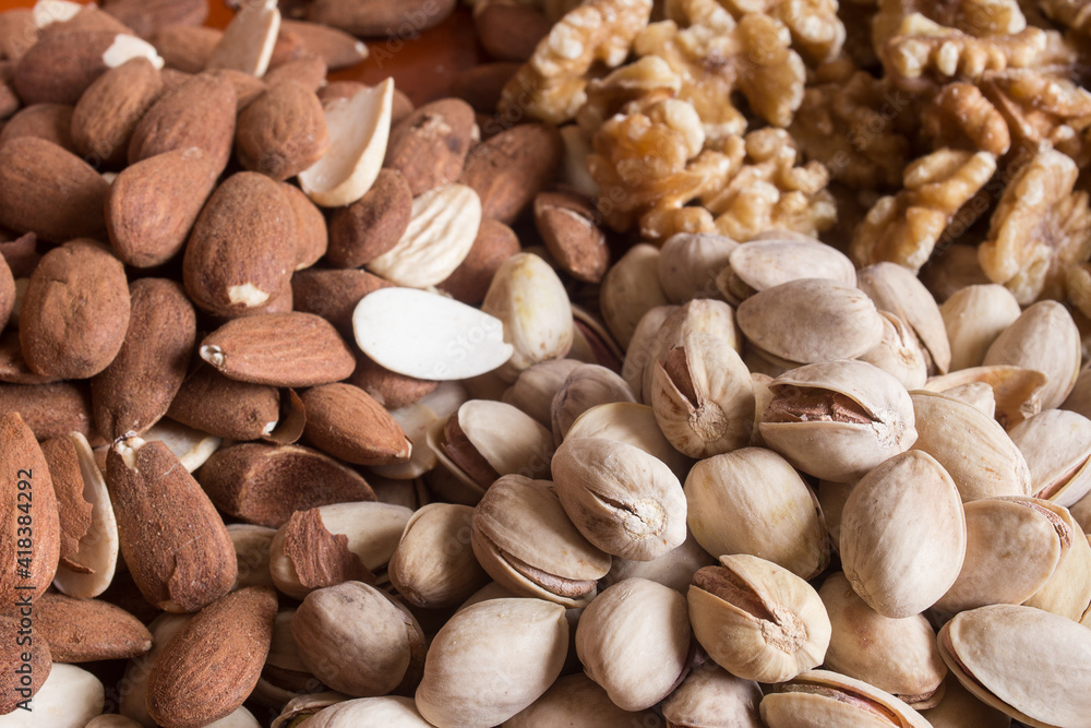 Close-up of some pistachios with some almonds on the side and walnuts out of focus in the background. Healthy food.