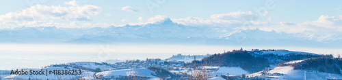 Italy Piedmont: row of wine yards, unique landscape in winter with snow, rural village on hill top, italian historical heritage nebbiolo grape agriculture