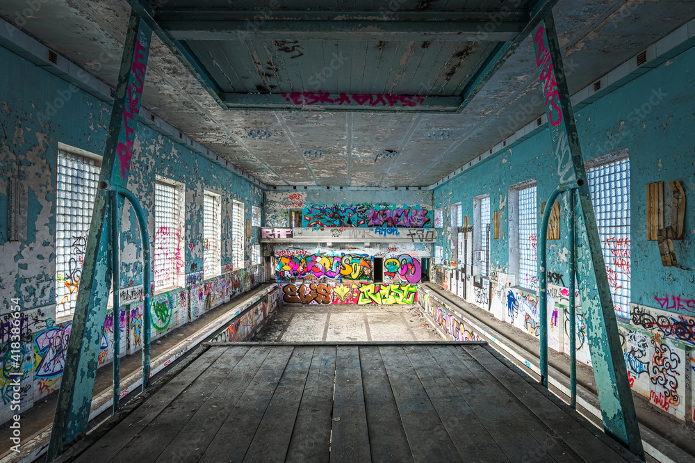 Abandoned Soviet time swimming pool and sports hall complex. Colorful graffiti paintings on the walls. Urban exploration.