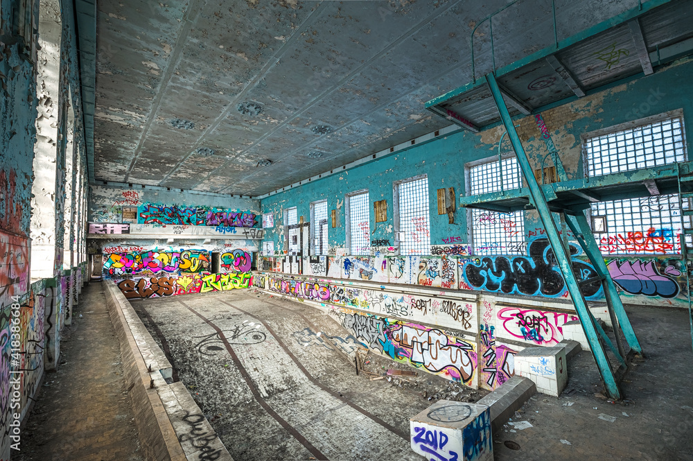 Abandoned Soviet time swimming pool and sports hall complex. Colorful graffiti paintings on the walls. Urban exploration.