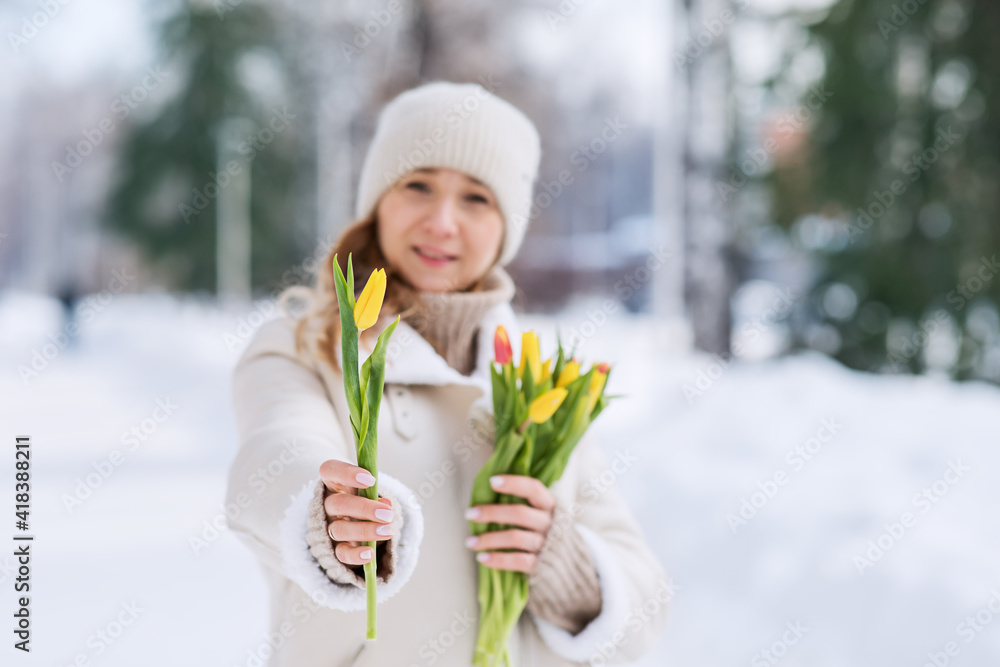 A girl with a bouquet of yellow and pink tulips on a walk on a sunny winter day. Flowers for International Women's Day. The nature of Siberia in Russia. A girl with a bouquet of yellow and pink tulips on a walk on a sunny winter day. Flowers for International Women's Day. The nature of Siberia in Russia.
