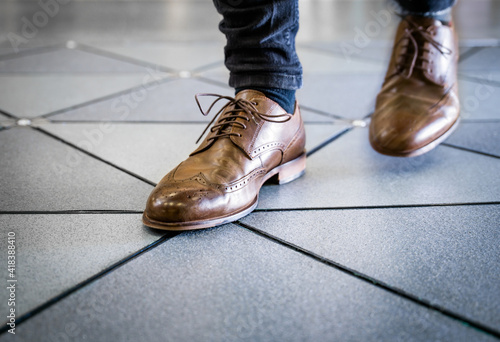 Feet in pair of brogues on tiled flooring photo