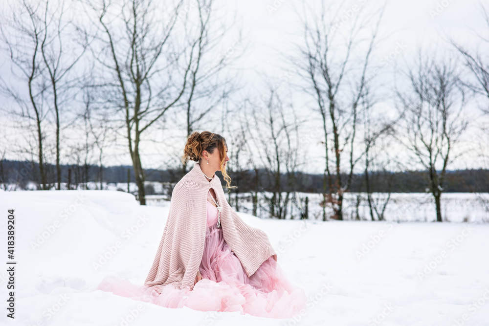 Eine wunderschöne sitzt im Schnee im Rosa Tüllkleid sitzt erwartungsvoll und Schauet zur Seite