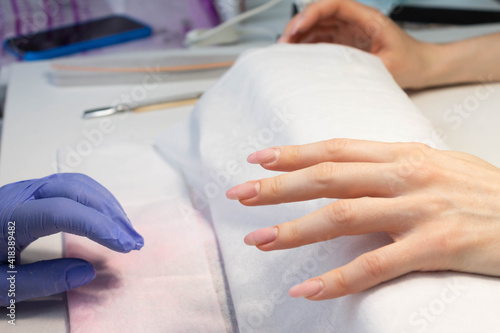 Manicure procedure. The process of strengthening natural nails with gel polish by a manicure master.