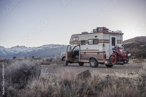Campervan carrying touring motorcycle behind parked in desert, Sierra Nevada, Bishop, California, USA