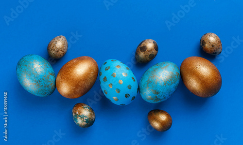 Blue and golden modern easter eggs in line on a blue background. Top view. Easter concept.