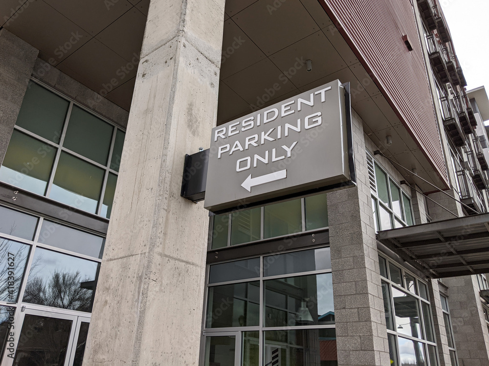 a large 'Resident Parking' sign on a brick wall outside a parking garage a large 'Resident Parking' sign on a brick wall outside a parking garage