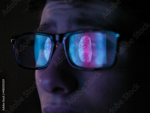 Cyber Security, reflection in spectacles  of access information being scanned on computer screen, close up of face photo