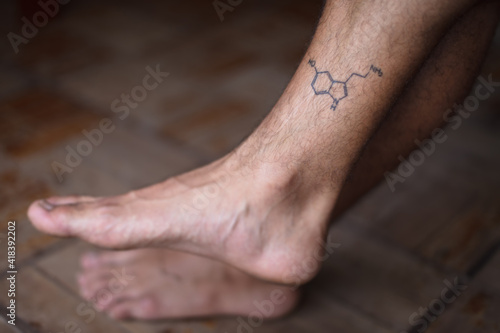 Tattoo of molecule serotonin on shin of man photo