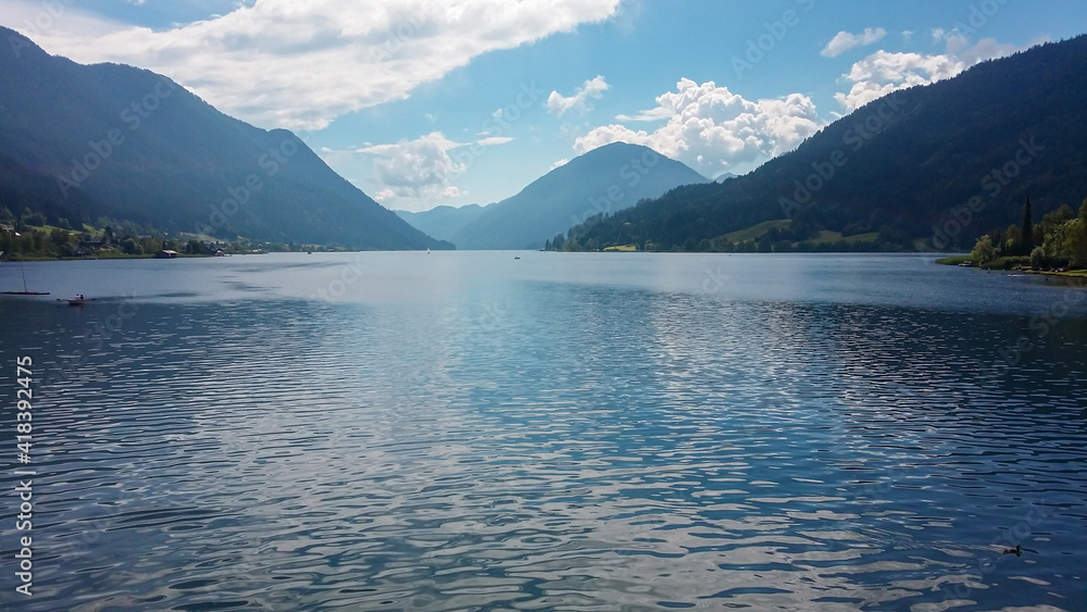 An idyllic view on the Weissensee lake surrounded by the Austrian Alps. endless chains of the mountains around. The surface of the lake is calm and reflecting the Alps. Joyfulness and happiness.