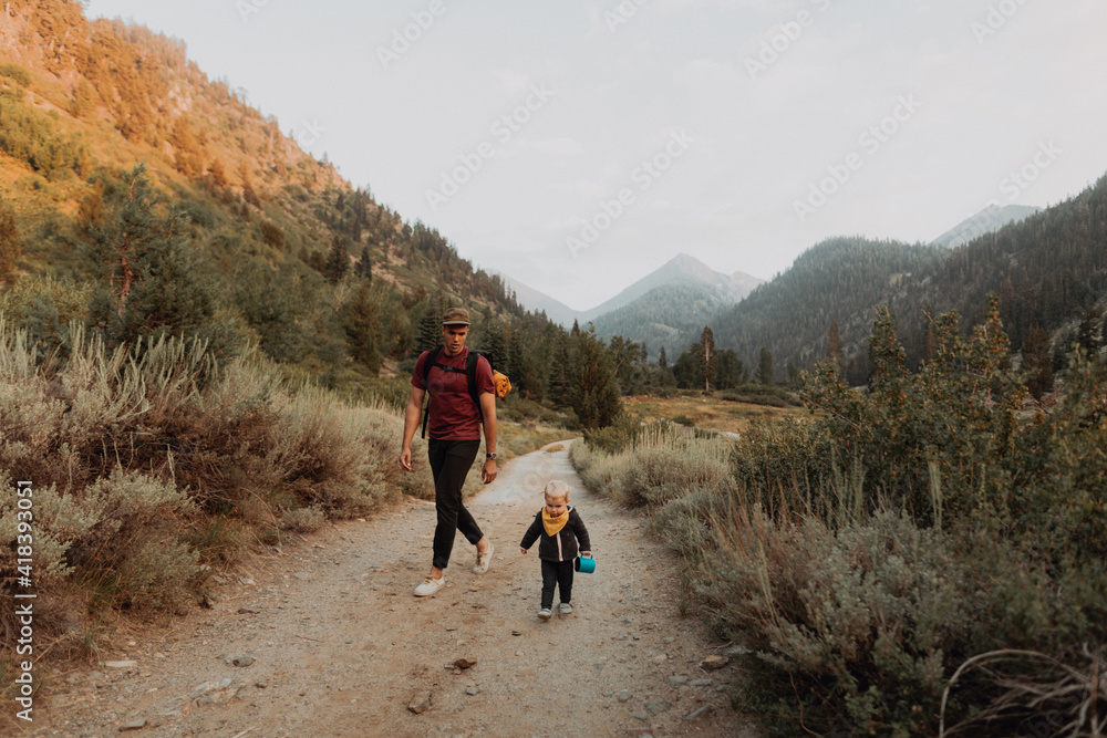 Female toddler and young man walking along rural road, Mineral King, California, USA Female toddler and young man walking along rural road, Mineral King, California, USA