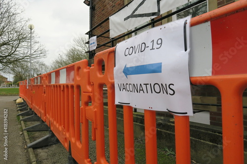 Covid-19 Vaccination signs to Vaccination clinic this way with blue arrow. Homemade signage found in the UK suburbs, DIY notice tells public which way to go for help during the coronavirus pandemic 