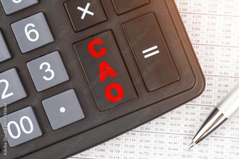 On the table is a report, a pen and a calculator, on the big key of which is written - CAO On the table is a report, a pen and a calculator, on the big key of which is written - CAO