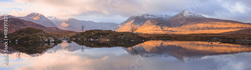 An inspiring wide panorama mountain landscape reflected on a calm peaceful lake at Rannoch Moor near Glencoe in the Scottish Highlands, Scotland.