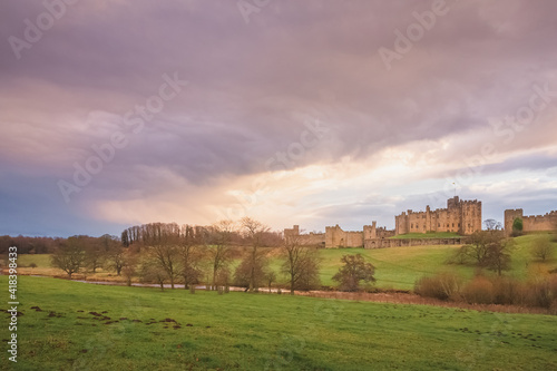 Dramatic and colourful sunset or sunrise clouds above the Englisgh Northumberland  countryside with view of River Aln and Alnwick Castle, England.