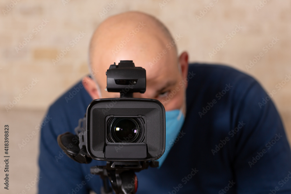 Man wearing face mask, looking to view finder of the camera and filming. Man wearing face mask, looking to view finder of the camera and filming.