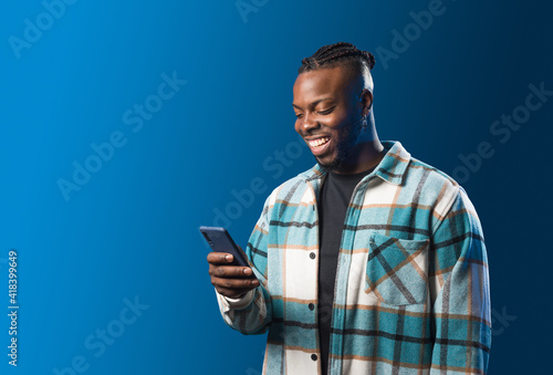 Foto Handsome black man looking at mobile smiling.