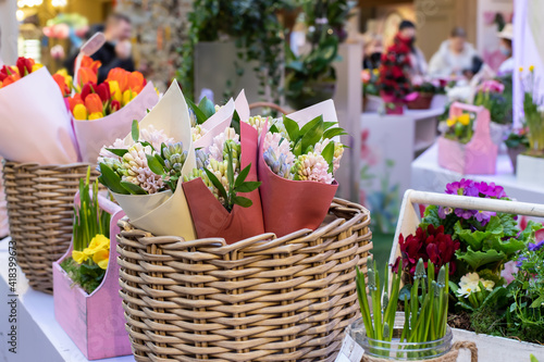Sale of flowers for the spring holidays. Bouquets of hyacinths wrapped in paper in a wicker basket on the counter.