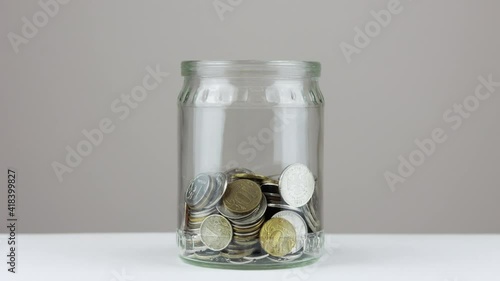Coins in the glass jar - stop motion animation. Saving money concept.