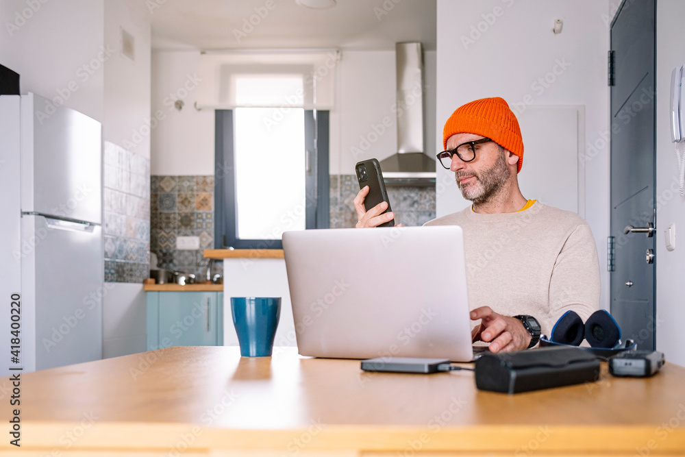 Man working from home on a laptop computer sitting at a desk surfing the internet Man working from home on a laptop computer sitting at a desk surfing the internet