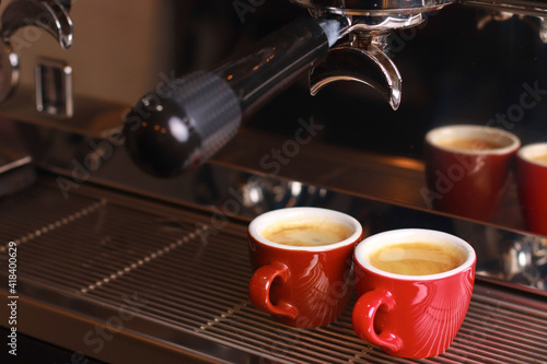 coffee cups stand inside the coffee machine on a grid  fresh coffee is poured inside the cups