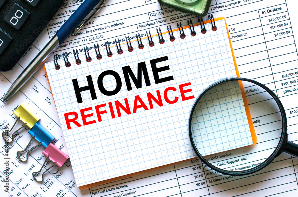 The notebook with the text Home Refinance lies on the financial tables with a calculator a magnifying glass The notebook with the text Home Refinance lies on the financial tables with a calculator a magnifying glass