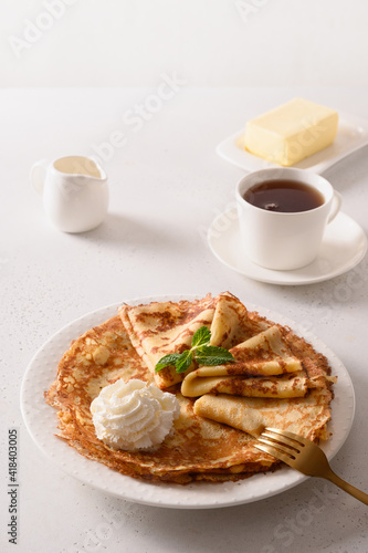 фотографія Russian thin pancakes or blini with whipped cream on white