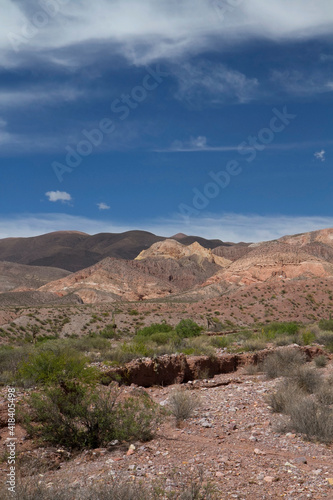 Travel. Altiplano landscape. View of the arid desert, colorful rock and sandstone formations under a beautiful blue sky with clouds.