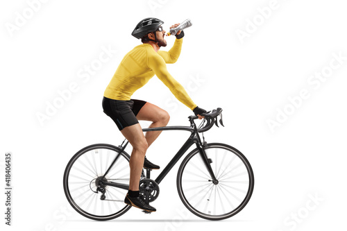 Fototapeta Naklejka Na Ścianę i Meble -  Profile shot of a male athlete riding a bike and drinking from a bottle
