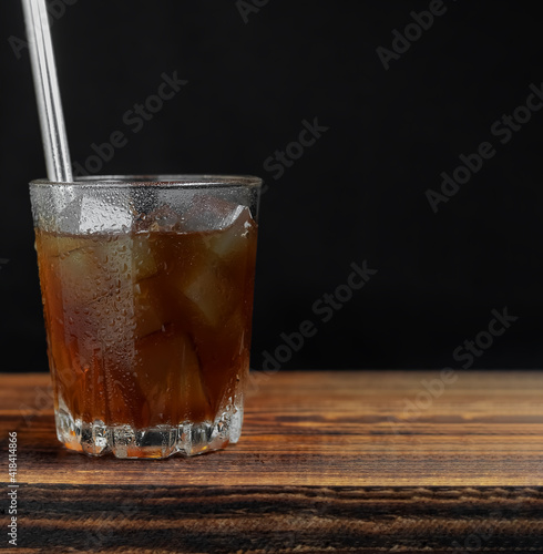 Wallpaper Mural Cold coffee with ice cubes on a wooden board. There are drops on the walls of the glass. Black background. Copy space Torontodigital.ca