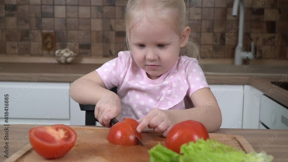Little child girl learns to cut vegetables with a knife in the kitchen Little child girl learns to cut vegetables with a knife in the kitchen