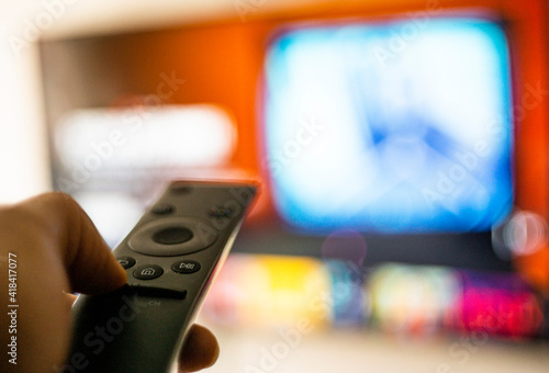 Una persona viendo películas por internet vía streaming en la sala con un control remoto de televisión en su mano photo