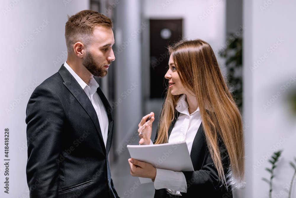 Business people discussing project while standing at the corrido Business people discussing project while standing at the corrido