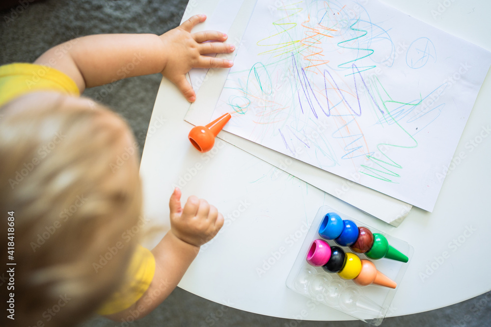 a child painting on a sheet on a table at home The child has colored paints and is learning with the montessori method a child painting on a sheet on a table at home The child has colored paints and is learning with the montessori method