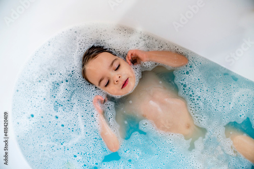Valokuvatapetti Toddler girl laying in bubble bath with eyes closed