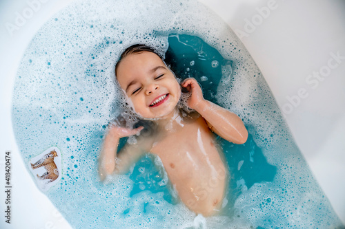 Tela Happy, smiling girl taking bubble bath in bathtub