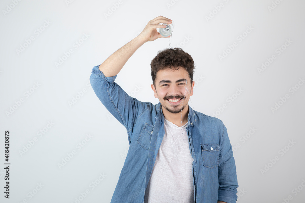 Photo of a smiling attractive man standing and holding a glass jar Photo of a smiling attractive man standing and holding a glass jar