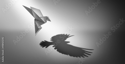 Vision and ambition as a business symbol for leadership power and success metaphor for growth as an origami paper bird casting a shadow of powerful real wings photo