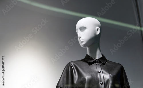 Female mannequin in the window of a fashionable clothing store. Minimalism and contrasting lighting, free space for an inscription. In the turn of the head, hidden emotions can be seen.