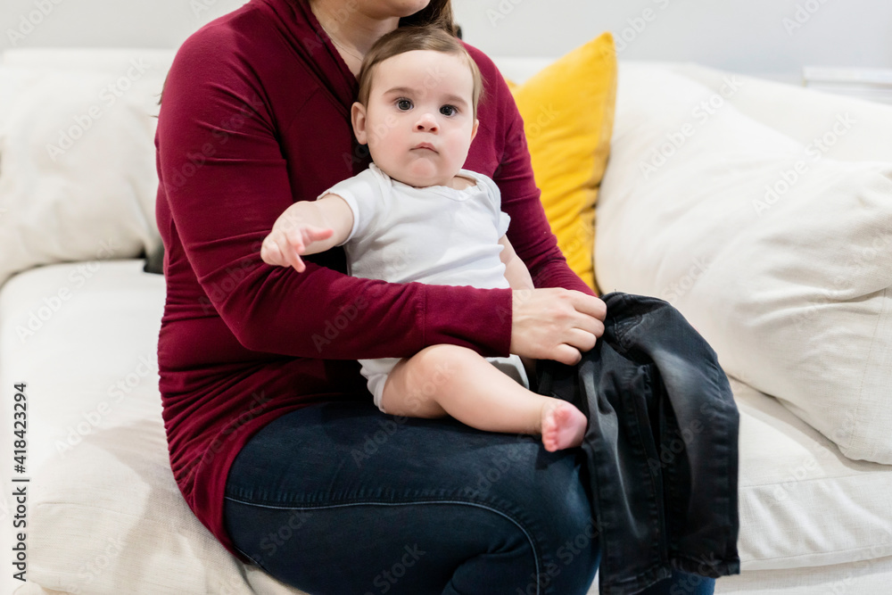 Mom changing baby boy's clothes on couch in home living room Mom changing baby boy's clothes on couch in home living room