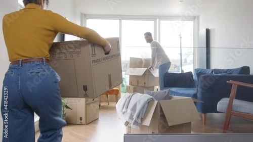 Portrait of loving young mixed ethnicity couple sitting on floor in lounge of new home hugging as they unpack removal boxes together